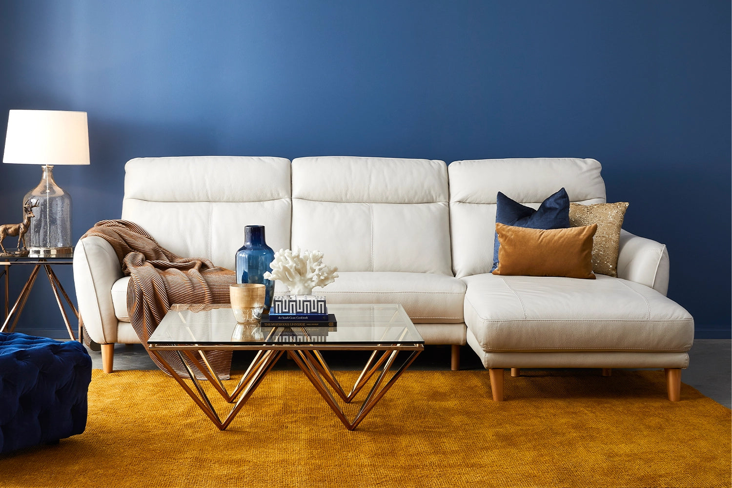 White sofa with decorative pillows in a living room setting with a blue wall and yellow rug.